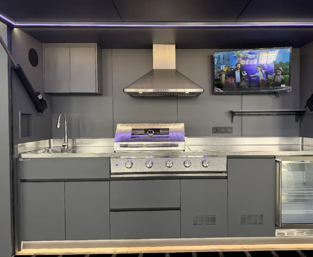 Unutrašnjost outdoor kuhinje s napom, roštiljem, sudoperom i TV-om